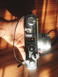 Close-up of hand holding camera on table