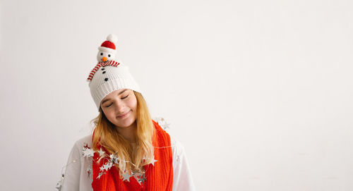 Funny young girl in a christmas hat with a snowman and a red scarf.