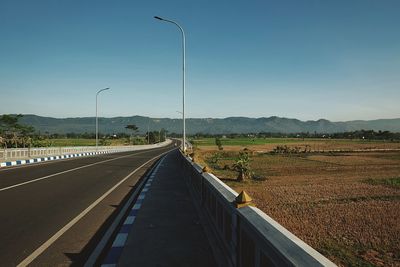 Road leading towards mountain against clear sky