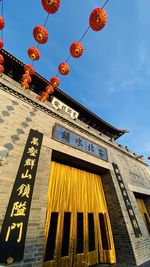 Low angle view of lanterns hanging by building against sky