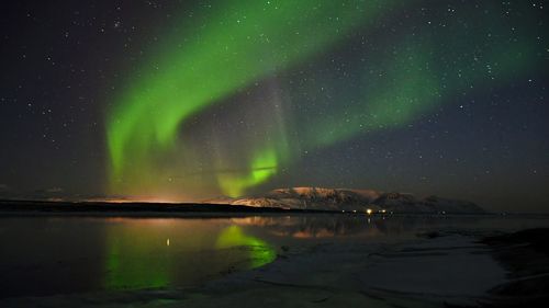 Scenic view of the northern lights reflected in the waters of the icelandic fjord