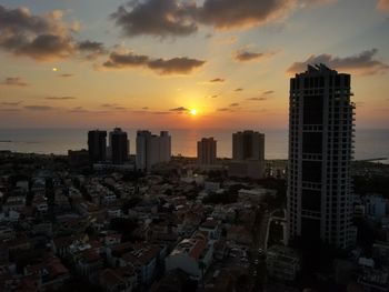 Modern buildings in city against sky during sunset