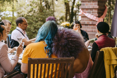 Rear view of lgbtq friends sitting together during dinner party in back yard