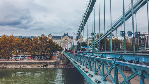 Bridge over river in city against sky