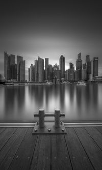 Buildings by river against sky in city