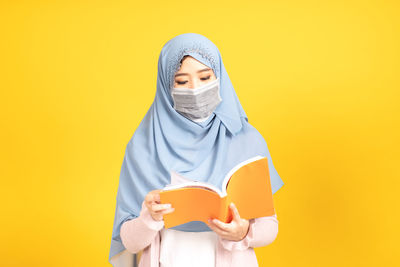 Portrait of man wearing mask against yellow background