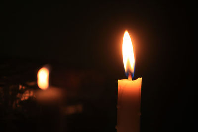 Close-up of illuminated candle in darkroom