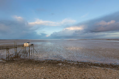 Scenic view of sea and fishing hut against sky