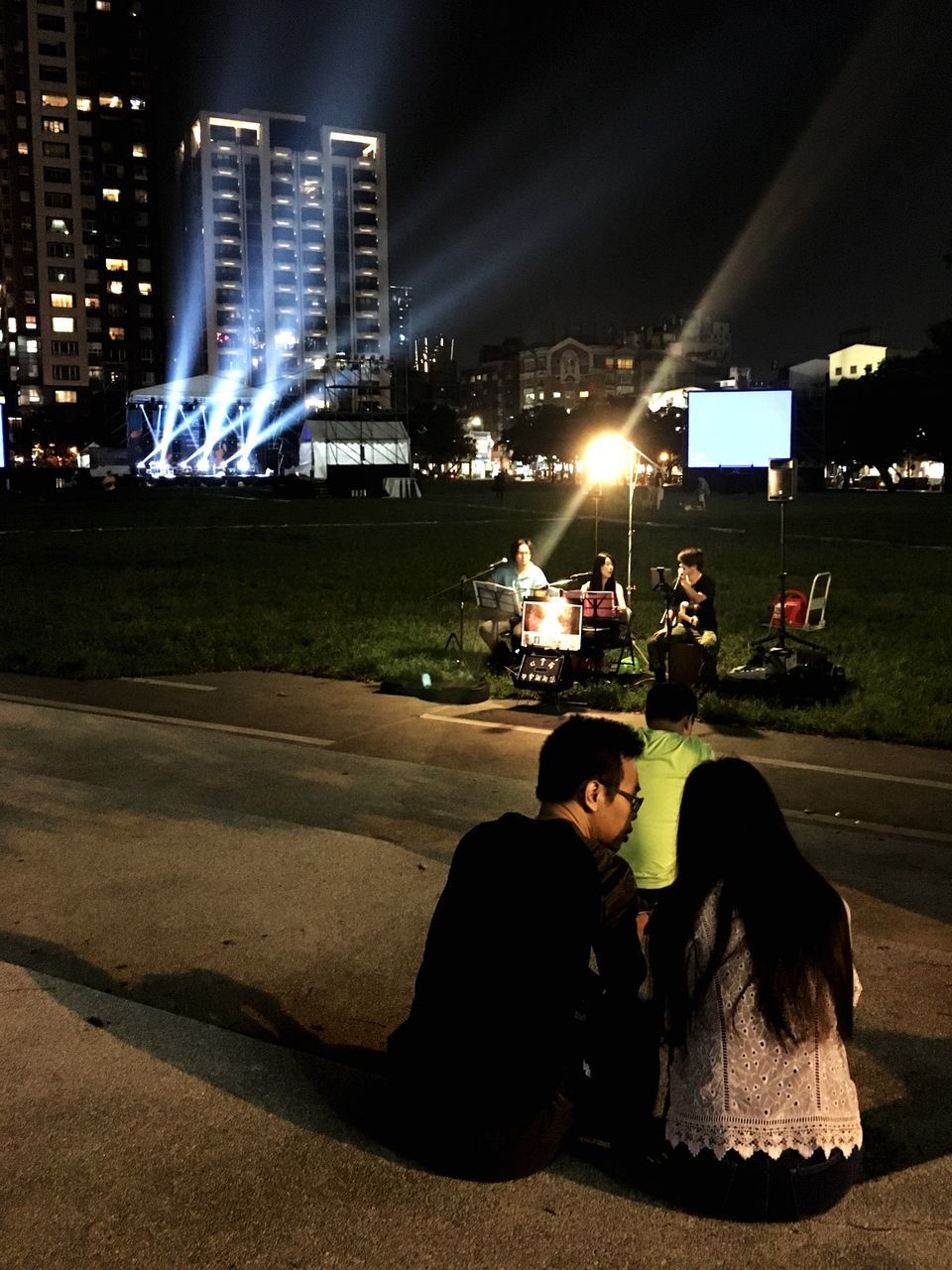 WOMAN SITTING ON ILLUMINATED CITY AT NIGHT