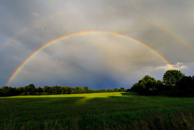 Scenic view of rainbow over field against sky