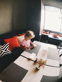 High angle view of girl using phone on table at home