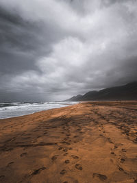 Scenic view of beach against cloudy sky