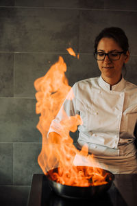 Female chef is making flambé in the kitchen