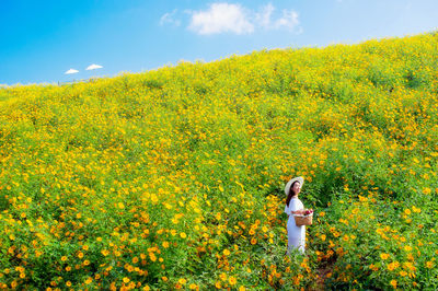 Woman standing on yellow flowering plants on field