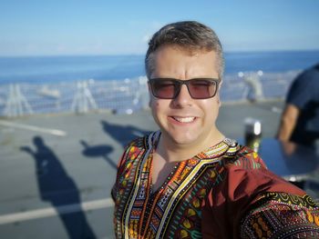 Portrait of smiling man at beach against sky