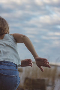 Rear view of woman dancing against sky