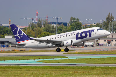 Airplane flying over airport runway against sky