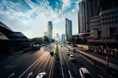 Vehicles on road amidst buildings in city against sky