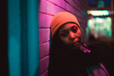 Portrait of woman standing by wall at night