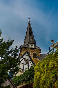 Low angle view of trees and building against sky