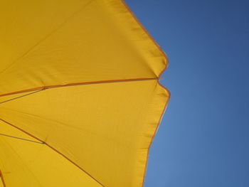 Low angle view of yellow umbrella against clear blue sky