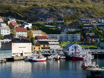 Sailboats moored in river by houses in city