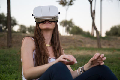 Young woman using virtual reality simulator while enjoying at park