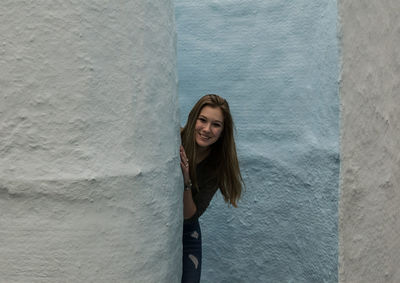 Portrait of young woman leaning against wall