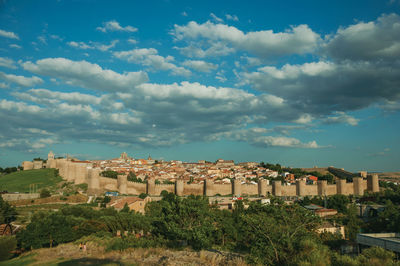 City landscape with large stone wall and towers over the hill encircling avila, in spain.