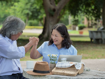 Couple doing fist bump while sitting at table in park