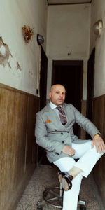 Portrait of man sitting on chair in corridor