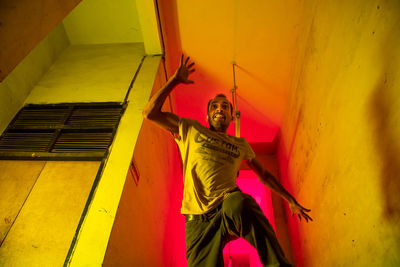 Portrait of woman standing against yellow wall