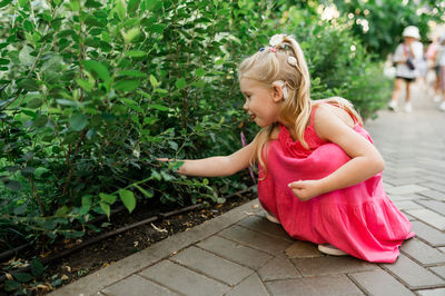 Side view of young woman standing against plants