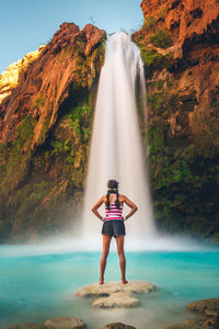 Full length of woman standing against waterfall