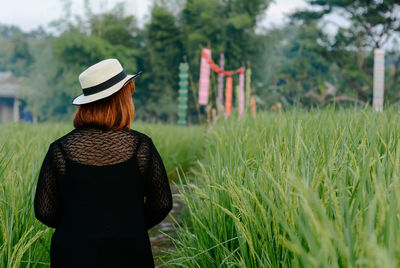 Rear view of woman standing on grassy field