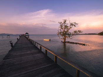 Scenic view of infinity long wooden pier boardwalk over seawater at sunset. koh mak island, thailand