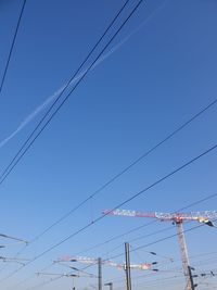 Low angle view of power lines against clear blue sky