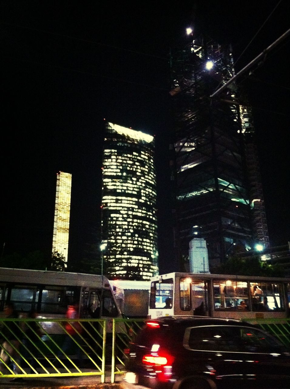 illuminated, night, building exterior, architecture, built structure, city, street, transportation, skyscraper, land vehicle, city life, street light, city street, car, road, low angle view, lighting equipment, modern, outdoors, sky