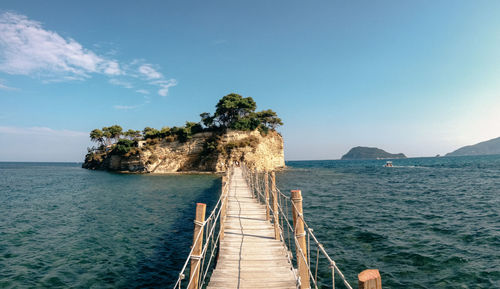 Footbridge over sea against sky