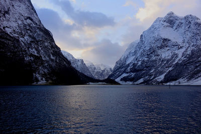 Scenic view of lake by snowcapped mountains against sky
