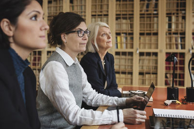 Female lawyers listening in meeting while sitting at table