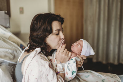 New mom in hospital kissing newborn son hand