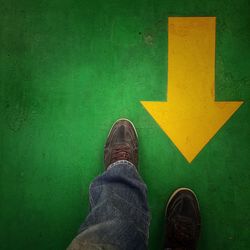 Low section of man standing on green sign