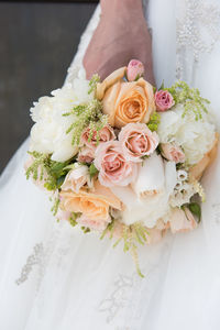 Midsection of bride holding bouquet