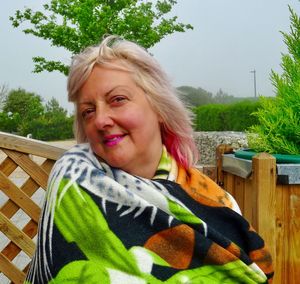 Portrait of woman wrapped in blanket while sitting against trees