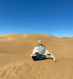 Rear view of man on desert against clear sky