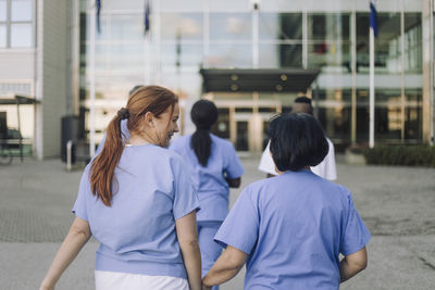 Female trainee talking with senior doctor while walking towards hospital building