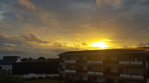 Houses in city against sky during sunset