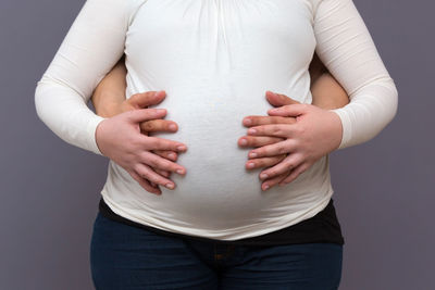 Midsection of woman standing against white background