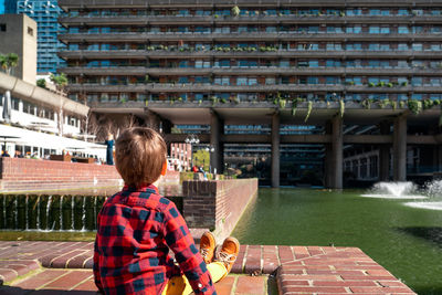 Rear view of boy sitting against building